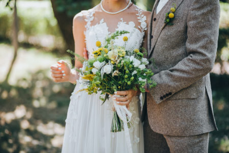 Bride and groom dressed in gray with yellow floral accents