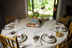 Stack of books in the center of the table with floral arrangement on top