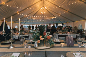 Tent with cafe bulbs, string lights, and chandelier for wedding reception