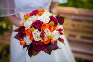 Bride holding autumn wedding bouquet with colorful roses