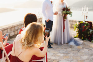 Wedding guest taking photos of couple during ceremony