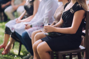 Wedding guest holding a glass of champagne during ceremony