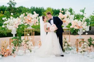 beautiful bride and groom in the wedding ceremony area of live white and pink flowers. decoration and organization of celebrations in the open air.